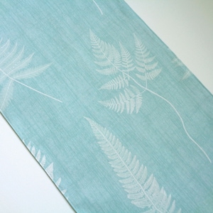 May include: A light blue table runner with a white fern pattern.