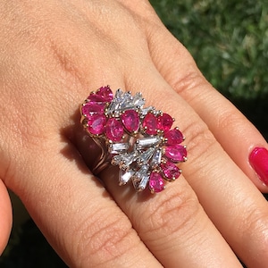 May include: A ring with a large pink ruby and diamond cluster. The ring is set in white gold and has a heart-shaped design.