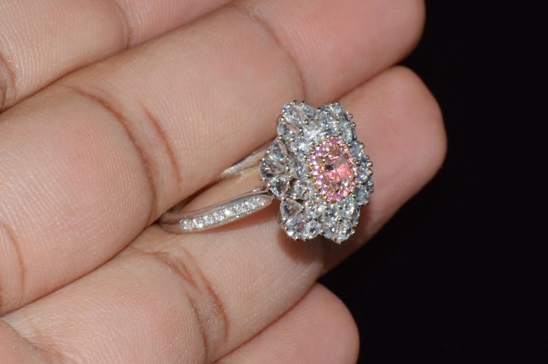 Puede incluir: Un anillo de plata con un dise&ntilde;o de flor rosa y blanca. La flor tiene una piedra central rosa grande rodeada de piedras blancas m&aacute;s peque&ntilde;as.