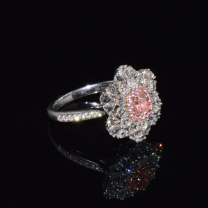 Puede incluir: Un anillo de plata con un dise&ntilde;o de flor de diamantes rosa y blanco.