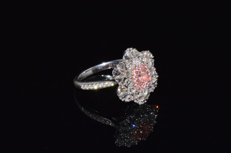 Puede incluir: Un anillo de plata con un dise&ntilde;o de flor de diamantes rosa y blanco.