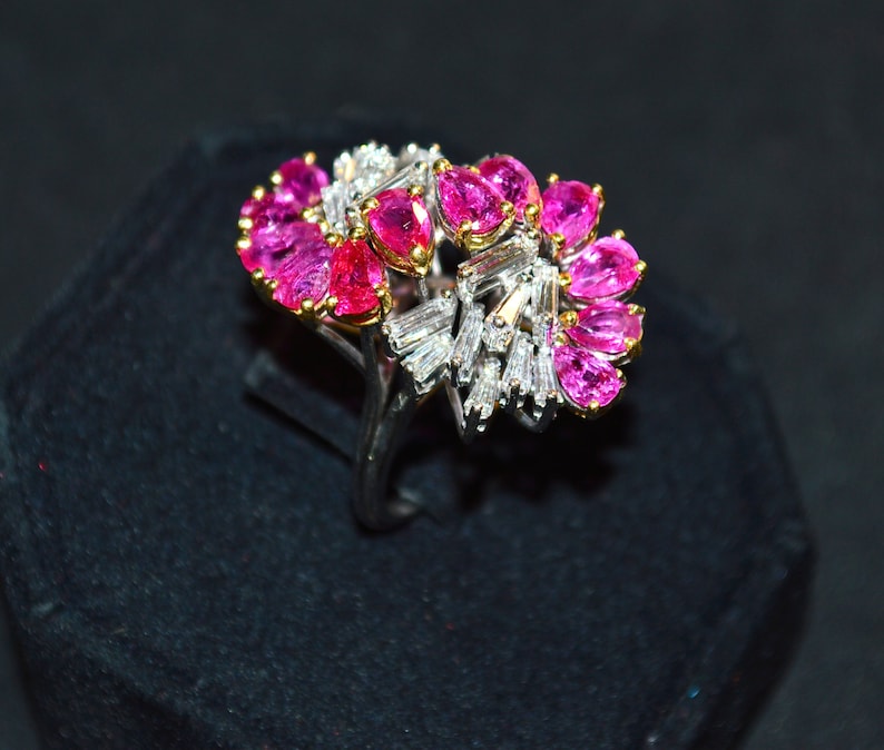 May include: A ring featuring a cluster of pink gemstones and baguette-cut diamonds set in a silver band.