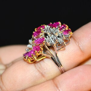 May include: A ring featuring a cluster of pink rubies and diamonds set in a gold and white metal band.