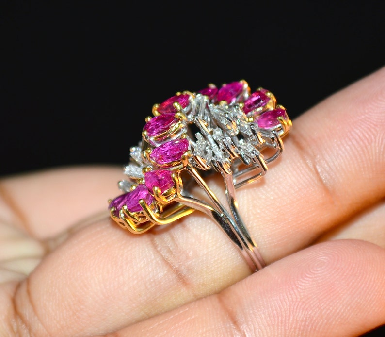 May include: A ring featuring a cluster of pink rubies and diamonds set in a gold and white metal band.