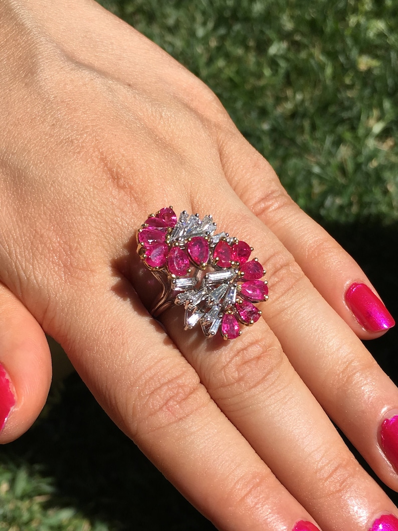 May include: A ring featuring a large pink ruby and diamond cluster. The ring is set in white gold and has a heart-shaped design.