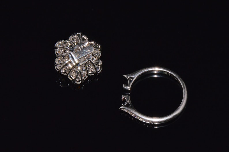 Puede incluir: Un anillo de plata con una piedra grande, redonda, similar a un diamante, engastada en un dise&ntilde;o con forma de flor. El anillo se muestra con el engaste retirado, revelando la banda de metal.