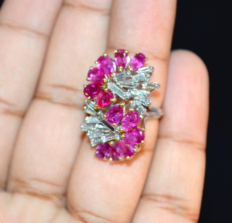 May include: A ring featuring a cluster of pink gemstones and baguette-cut diamonds set in white gold.
