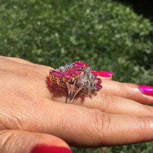 May include: A gold ring featuring a cluster of pink rubies and diamonds. The ring is set in a prong setting and has a delicate band.