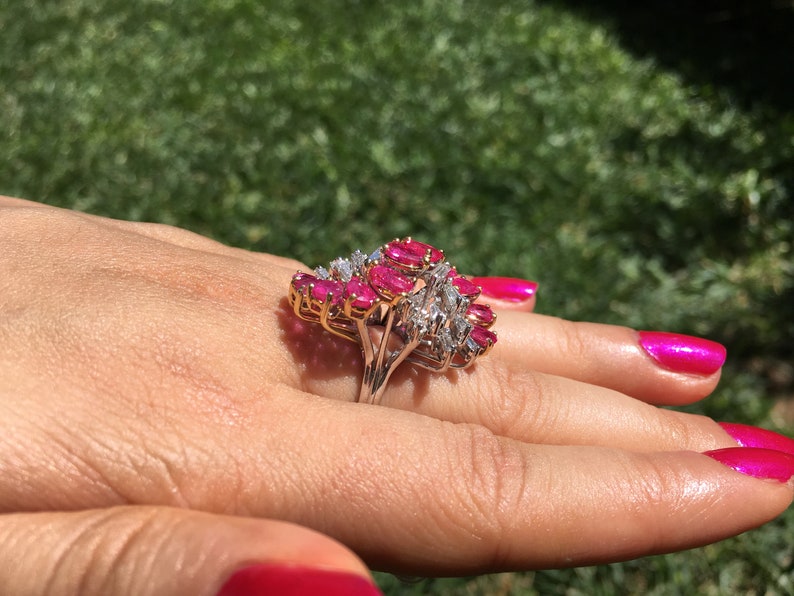 May include: A gold ring featuring a cluster of pink rubies and diamonds. The ring is set in a prong setting and has a delicate band.