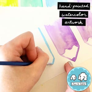 May include: Hand-painted watercolor artwork in progress. A hand holds a blue pencil, creating a light blue outline on white paper. The artwork features purple watercolor pencil shapes. The image includes the text "hand-painted watercolor artwork".