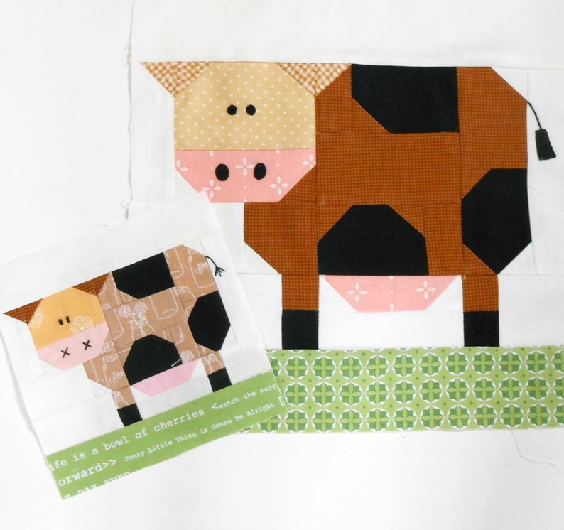 May include: Two patchwork fabric cows, one larger than the other, with black and brown spots. The larger cow is standing on a green patterned fabric strip. The smaller cow is on a white background with a text quote: "Life is a bowl of cherries.  Swatch the sunr.  Every little thing is gonna be alright.  Forward>>"