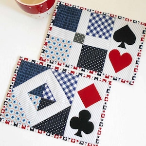 May include: Two handmade fabric coasters with a red, white, and blue patchwork design. Each coaster features a different playing card symbol: a spade, a heart, a diamond, and a club.