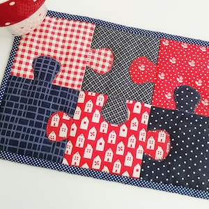 May include: A red, white, and blue patchwork coaster with a puzzle piece design. The coaster is made of fabric and has a blue polka dot border.