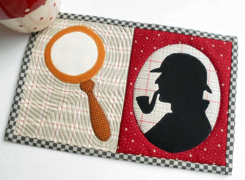 K&ouml;nnte beinhalten: Ein gesteppter Untersetzer mit einer Lupe und einer Silhouette eines Detektivs mit einer Pfeife auf rotem Hintergrund. Der Untersetzer hat einen karierten Rand.
