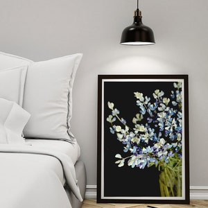 May include: A framed print of a bouquet of blue and white flowers against a black background. The flowers are in a clear glass vase.