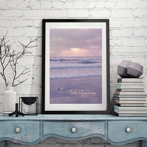 Pode incluir: Uma impress&atilde;o emoldurada de uma cena de praia com um c&eacute;u roxo e ondas quebrando na costa. O texto "Breathe, smile and be happy..." est&aacute; impresso na parte inferior da imagem.