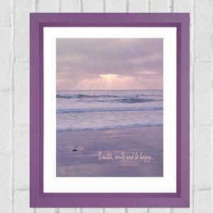 Pode incluir: Impress&atilde;o emoldurada em roxo com uma fotografia de uma cena de praia com um c&eacute;u roxo claro e ondas. O texto "Breathe, smile and be happy..." est&aacute; impresso na parte inferior da imagem.