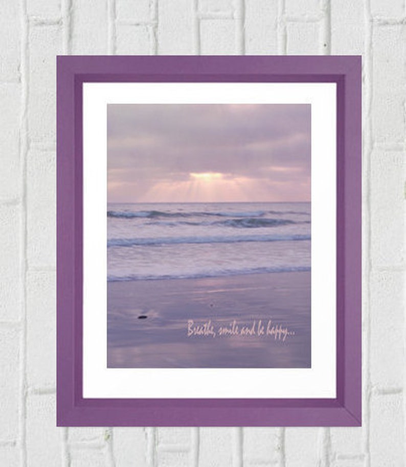 Pode incluir: Impress&atilde;o emoldurada em roxo com uma fotografia de uma cena de praia com um c&eacute;u roxo claro e ondas. O texto "Breathe, smile and be happy..." est&aacute; impresso na parte inferior da imagem.