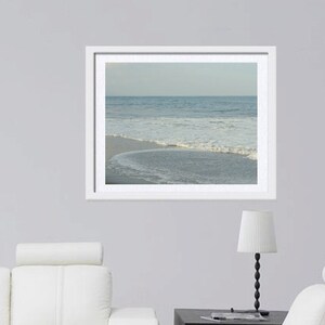 May include: A framed photograph of a beach scene with blue water and white waves crashing on the shore.