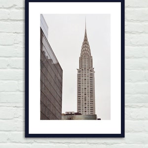 May include: A black and white photograph of a tall, pointed skyscraper with a decorative top. The building is in the center of the image and is surrounded by other buildings.
