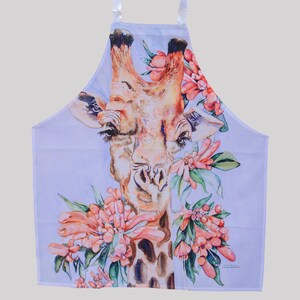 May include: A white apron with a watercolor illustration of a giraffe with pink and green flowers. The giraffe's head is in the center of the apron, and the flowers are around the giraffe's neck and head.