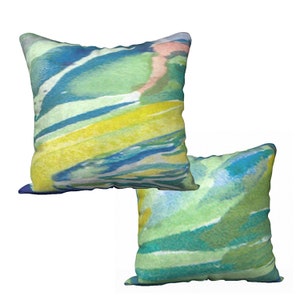 Könnte beinhalten: Zwei quadratische Kissen mit einem abstrakten Aquarell-Design in Blau, Grün und Gelb.