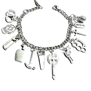 May include: Silver-toned charm bracelet featuring various miniature pendants. Charms include a skull, handcuffs, a cleaver, a hammer, a saw, an axe, a gun, brass knuckles, a grenade, and a straight razor. The bracelet is on a white background.