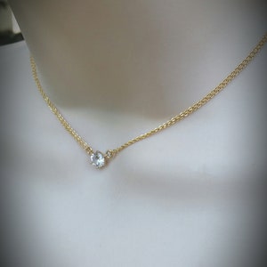 Puede incluir: Un delicado collar de cadena de oro con un solo colgante de cristal transparente.