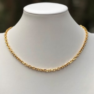 May include: A gold chain necklace with a simple, classic design. The chain is made of oval-shaped links.