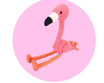 May include: A pink crocheted flamingo toy with black eyes and a white beak. The flamingo is sitting on a pink background.