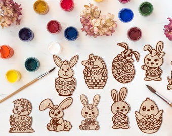 Pode incluir: Um conjunto de 11 recortes de madeira com tema de Páscoa, incluindo coelhos, pintinhos e ovos, prontos para serem pintados com tintas coloridas. Os recortes são perfeitos para artesanato e decoração para a Páscoa.