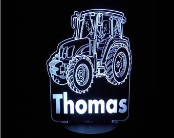 May include: White outline of a tractor with the name "Thomas" underneath. The tractor is illuminated from behind, creating a glowing effect.