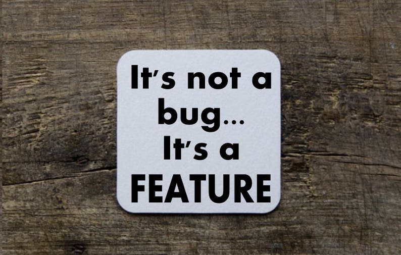 May include: White square coaster with black text that reads "It's not a bug... It's a FEATURE".