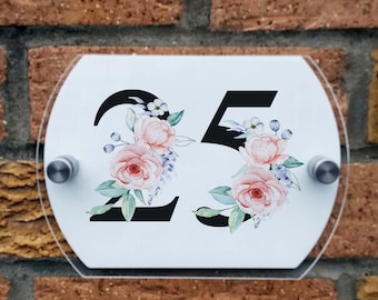 May include: White oval acrylic house number sign with black numbers "25" and pink watercolor floral design.