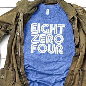 May include: A blue t-shirt with white text that reads "EIGHT ZERO FOUR" in a retro font style.