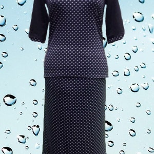 May include: A two-piece outfit consisting of a dark navy blue top and a matching skirt, both featuring a white polka dot pattern. The top has three-quarter length sleeves, and the skirt is a long, straight cut with a ruffled hem at the bottom.