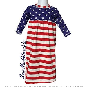 May include: A long-sleeved dress with a red, white, and blue American flag pattern. The top of the dress has a blue background with white stars, and the bottom of the dress has alternating red and white stripes. The dress has a gathered waist and long sleeves.