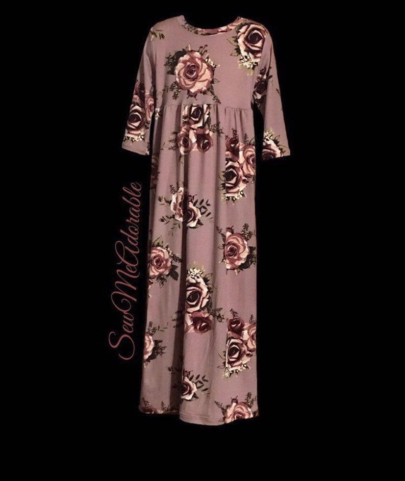 May include: A long-sleeved mauve dress with a floral print featuring pink and burgundy roses. The dress has a gathered waist and a relaxed fit.