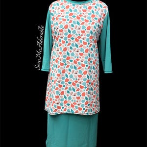 May include: A long-sleeve tunic featuring a white front panel with a repeating pattern of coral and teal seashells and starfish. The sleeves and lower section are solid teal. The text Sew Me Adorable is printed vertically on the left side.