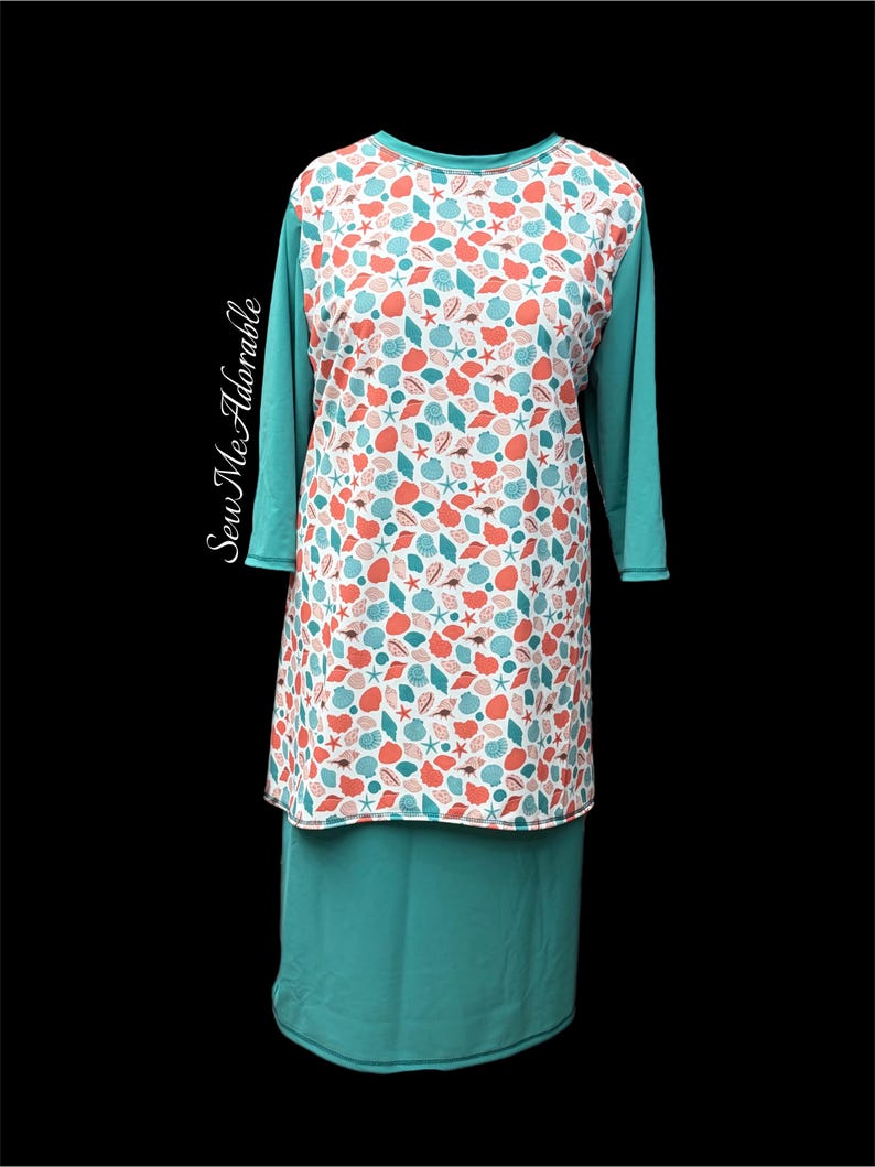 May include: A long-sleeve tunic featuring a white front panel with a repeating pattern of coral and teal seashells and starfish. The sleeves and lower section are solid teal. The text Sew Me Adorable is printed vertically on the left side.