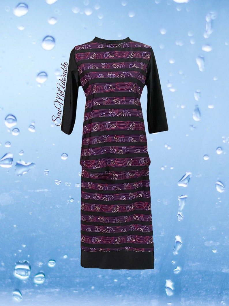 May include: A long-sleeved tunic and skirt set featuring a black and purple striped pattern with small white and red leaf motifs. The garment includes solid black sleeves and a solid black hem. The text SewMeAdorable is printed on the left side.