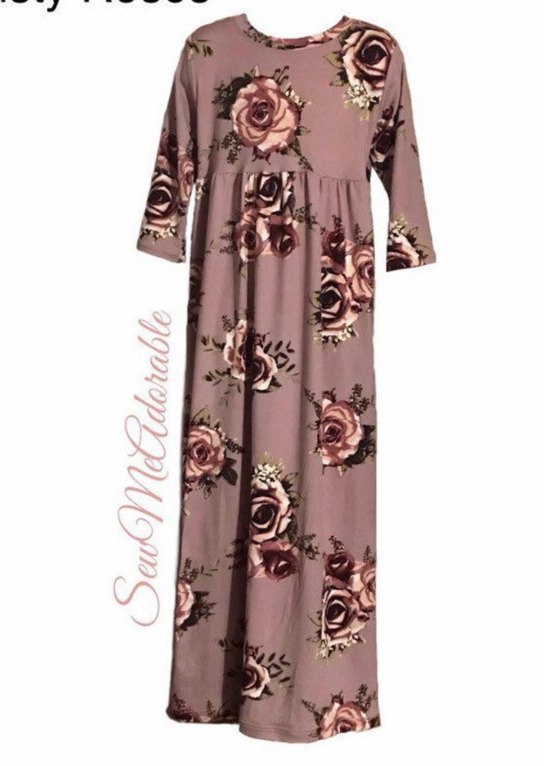 May include: A mauve long-sleeved dress with a floral print featuring pink and burgundy roses. The dress has a gathered waist and a flowing skirt.