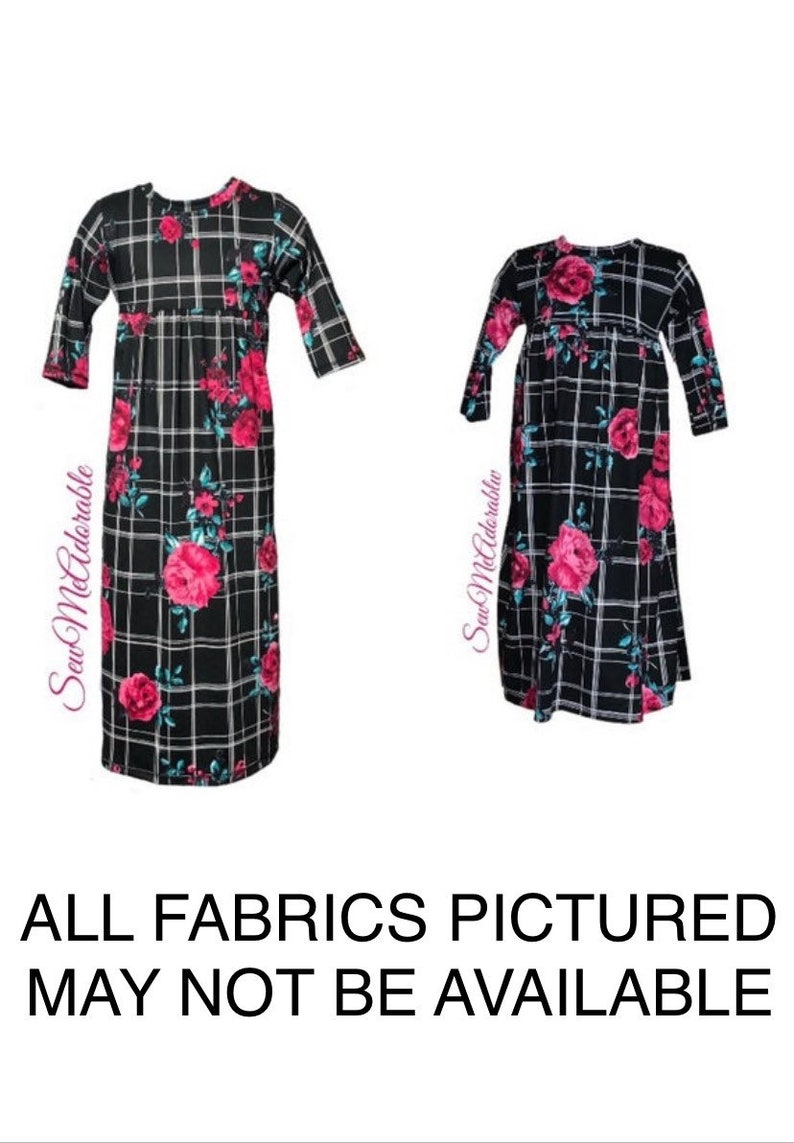 May include: Two black and white plaid dresses with pink floral designs. The dresses have 3/4 sleeves and a gathered waist.