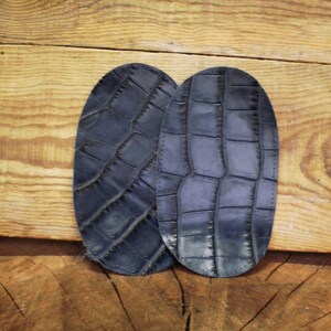 Puede incluir: Dos parches de cuero azul oscuro con un patrón de piel de cocodrilo.