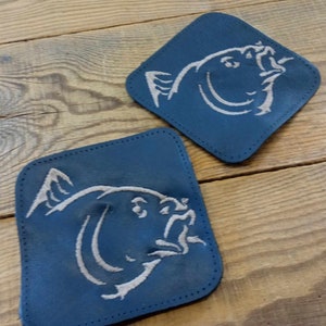 May include: Two blue fabric patches with white embroidered fish designs. The fish are facing to the right and have a detailed design.
