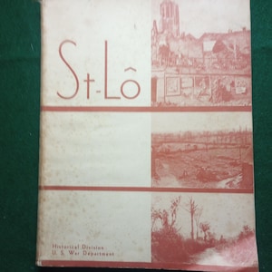 May include: A vintage book cover with the title "St. Lô" in red lettering. The cover features three black and white photographs of a town in ruins. The text "Historical Division U.S. War Department" is printed at the bottom of the cover.