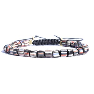 May include: A black cord bracelet with colorful striped beads. The beads are black, white, red, and blue.
