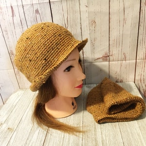 May include: A brown crocheted hat with a wide brim and a matching crocheted beanie. The hat is made with a speckled yarn.