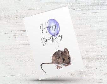 May include: A greeting card with a watercolor illustration of a brown mouse holding a purple balloon. The card says "Happy Birthday" in black cursive.