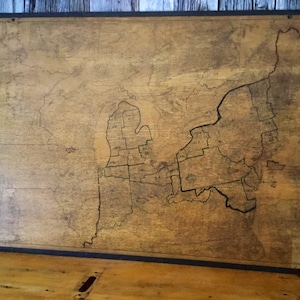 May include: A vintage wooden map of the Great Lakes region, with the borders of each state outlined in black ink. The map is mounted on a wooden frame and has a worn, aged appearance.